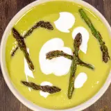 Crema di asparagi vellutata con asparagi arrostiti e un tocco di panna.
