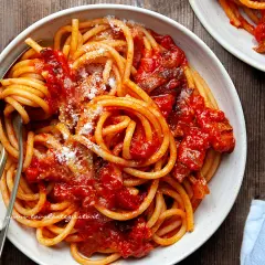 Un piatto fumante di bucatini all'amatriciana ricetta originale, conditi con guanciale croccante e pomodoro.