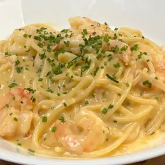 Spaghetti cremosi con gamberi e una spolverata di erba cipollina, un'invitante carbonara di mare.