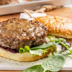Hamburger al forno succulento su pane con sesamo, insalata fresca e cipolla rossa.