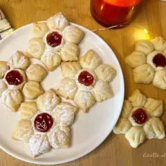 Deliziosi biscotti con marmellata a forma di fiore, spolverati di zucchero a velo, pronti per essere gustati.