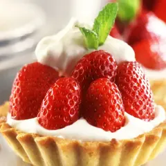Deliziosi dolci con fragole fresche e panna montata, guarniti con una fogliolina di menta.