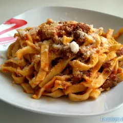 Un piatto di tagliatelle al ragù fumanti, condite con abbondante parmigiano grattugiato. Un classico della cucina italiana.