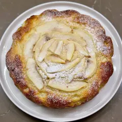Torta ricotta e pere dorata, con fette di pera disposte a raggiera e spolverata di zucchero a velo.