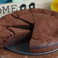 Un invitante dolce al cioccolato, cosparso di cacao, pronto per essere gustato. Sullo sfondo, una decorazione con la parola "HOME" e fiori gialli.