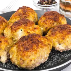 Golden brown zucchini and potato fritters on a black pan.