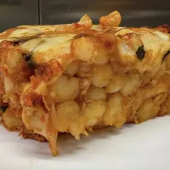 Porzione generosa di gnocchi al forno, dorati e filanti, con sugo e formaggio fuso.