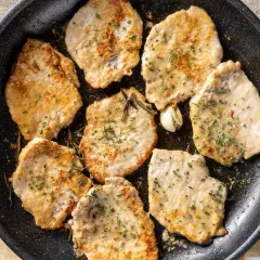 Fette di lonza di maiale in padella, dorate e morbide, insaporite con rosmarino e aglio.