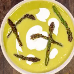 Crema di asparagi vellutata con asparagi arrostiti e un tocco di panna.