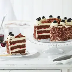 Una fetta di foresta nera torta, con strati di cioccolato, panna e ciliegie, accanto a una torta intera decorata.