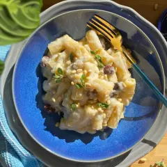 Piatto di pasta e cavolfiore cremoso, guarnito con pinoli e erbe aromatiche, pronto per essere gustato.