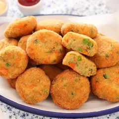 Un piatto pieno di polpette di verdure al forno, dorate e croccanti, con piselli e carote visibili all'interno.