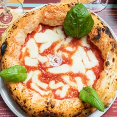 Impasto pizza napoletana con pomodoro, mozzarella filante e basilico fresco. La crosta è alta e alveolata, segno di una lievitazione perfetta.
