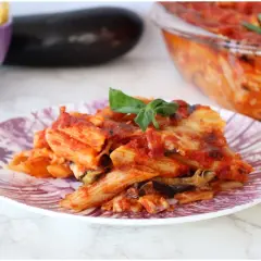Piatto di pasta alla siciliana con melanzane, pomodoro e basilico, appena sfornata.