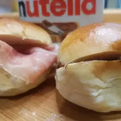 Due panini al latte, uno con prosciutto e l'altro con Nutella, pronti per essere gustati.