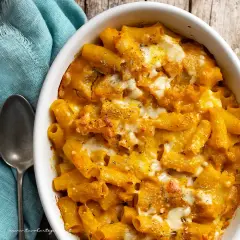 Piatto invitante di pasta con la zucca, gratinata al forno con formaggio filante e erbe aromatiche.