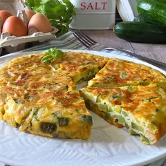 Una gustosa frittata di zucchine, dorata e soffice, con ingredienti freschi come uova e basilico.
