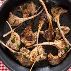 Costine di agnello in padella, dorate e succulente, pronte per essere gustate.