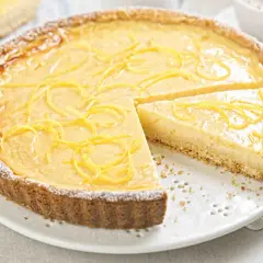 Una deliziosa crostata con crema pasticcera, guarnita con scorza di limone e spolverata di zucchero a velo. Perfetta per ogni occasione.