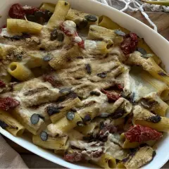 Piatto di pasta con carciofi alla siciliana, pomodori secchi e semi di zucca, gratinata al forno.