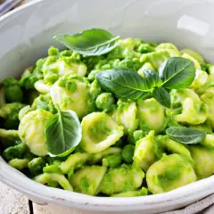 Orecchiette fatte in casa con crema di piselli e basilico fresco, un piatto primaverile invitante.