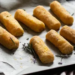 Crocchette di patate al forno dorate e croccanti, pronte per essere gustate. Profumano di rosmarino e sale grosso.