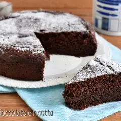 Torta al cioccolato e ricotta, soffice e golosa, spolverata di zucchero a velo. Una fetta invitante attende di essere gustata.