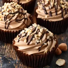 Cupcake con soffice crema di nocciole, decorato con cioccolato fuso e granella di nocciole tostate.
