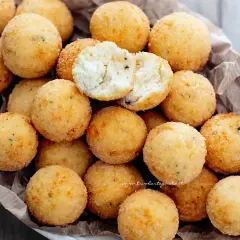 Un cesto pieno di croccanti polpette di ricotta, dorate e invitanti. Una è aperta, mostrando il morbido interno.
