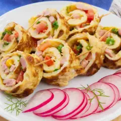 Rotolo di frittata ripieno di prosciutto, pomodoro e verdure, servito con fettine di ravanello.