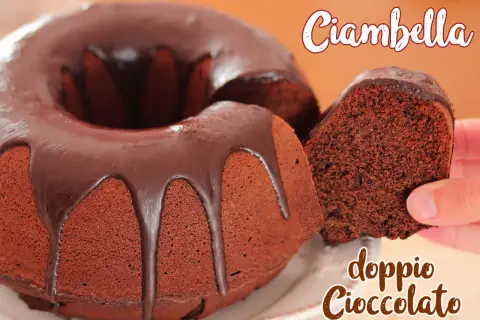 Ciambella al cioccolato, soffice e golosa, con una glassa lucida che cola. Una fetta viene sollevata, mostrando la sua consistenza.
