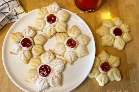 Deliziosi biscotti con marmellata a forma di fiore, spolverati di zucchero a velo, pronti per essere gustati.