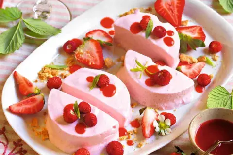 Delizioso semifreddo alle fragole, guarnito con fragoline di bosco, salsa rossa e foglioline verdi. Un dolce estivo perfetto.