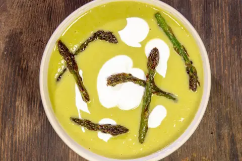 Crema di asparagi vellutata con asparagi arrostiti e un tocco di panna.