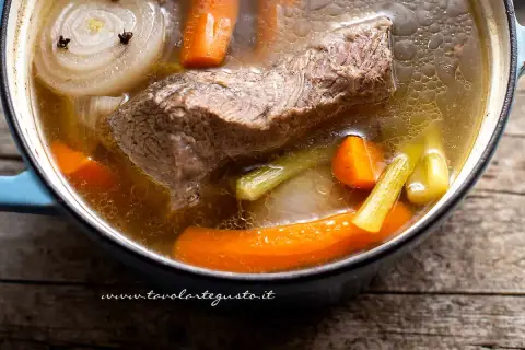 Un pezzo di carne succulenta cuoce lentamente in un brodo di carne aromatico, con carote, sedano e cipolla.