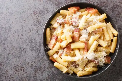 Rigatoni alla gricia fumanti, conditi con guanciale croccante e pecorino romano grattugiato, un classico della cucina romana.