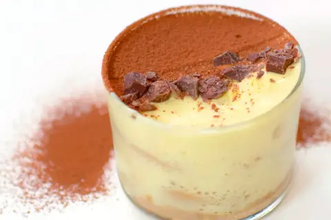 Un bicchiere di tiramisù, con cacao e scaglie di cioccolato. Perfetto per scoprire come si fa il tiramisù.
