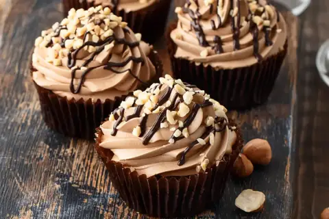 Cupcake con soffice crema di nocciole, decorato con cioccolato fuso e granella di nocciole tostate.