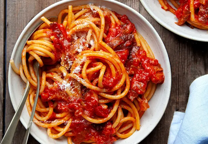 Un piatto fumante di bucatini all'amatriciana ricetta originale, conditi con guanciale croccante e pomodoro.