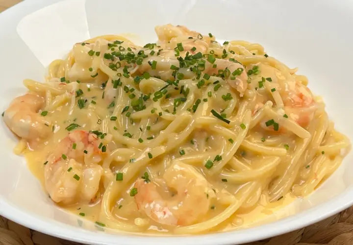 Spaghetti cremosi con gamberi e una spolverata di erba cipollina, un'invitante carbonara di mare.
