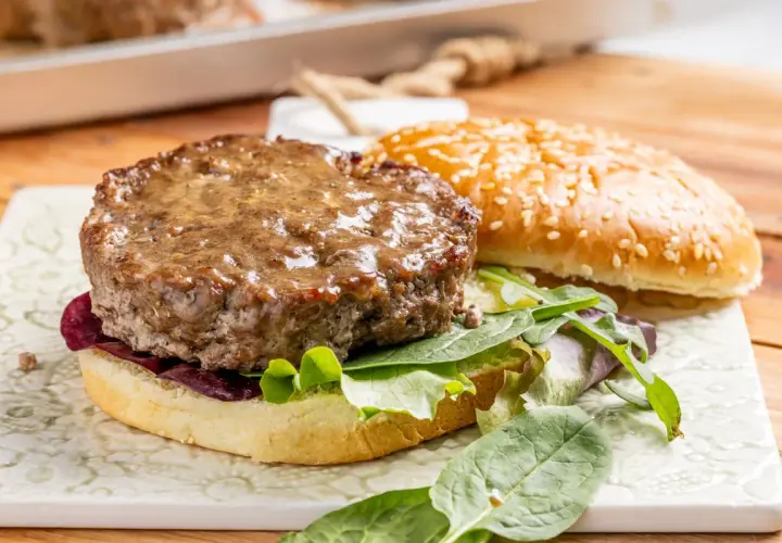 Hamburger al forno succulento su pane con sesamo, insalata fresca e cipolla rossa.