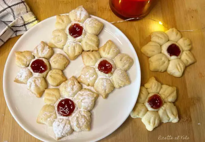 Deliziosi biscotti con marmellata a forma di fiore, spolverati di zucchero a velo, pronti per essere gustati.