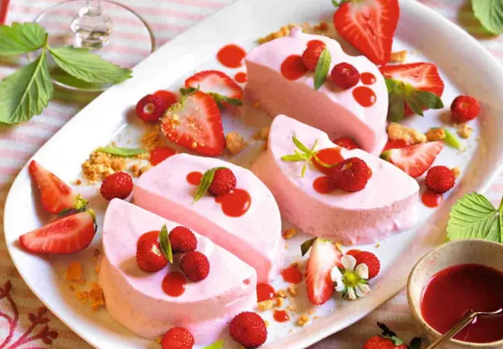 Delizioso semifreddo alle fragole, guarnito con fragoline di bosco, salsa rossa e foglioline verdi. Un dolce estivo perfetto.
