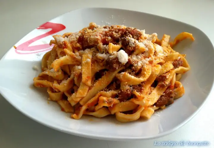 Un piatto di tagliatelle al ragù fumanti, condite con abbondante parmigiano grattugiato. Un classico della cucina italiana.