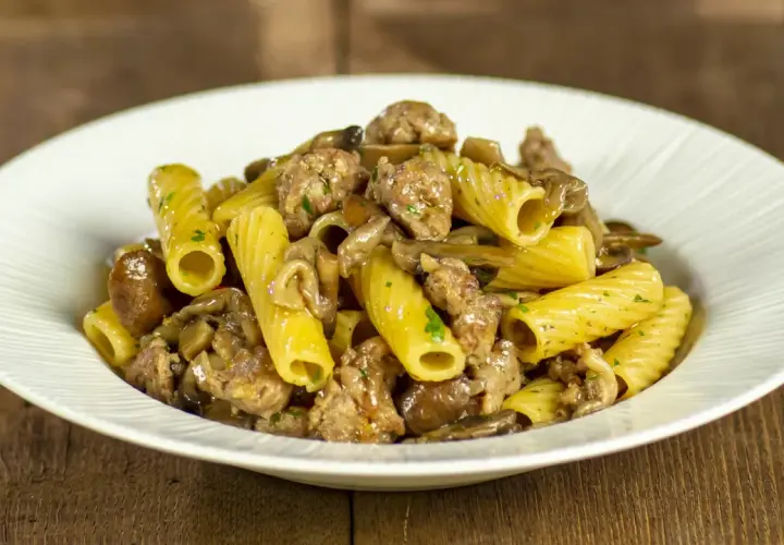 Piatto di pasta con funghi e salsiccia, un classico saporito.