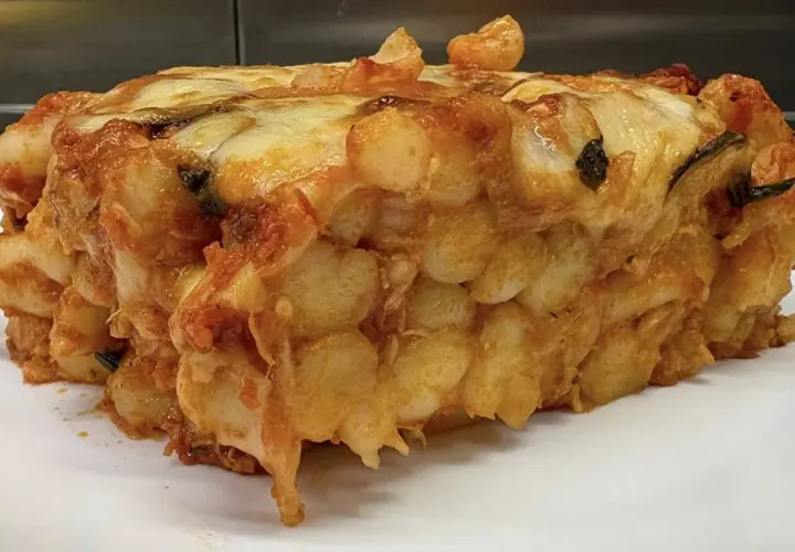 Porzione generosa di gnocchi al forno, dorati e filanti, con sugo e formaggio fuso.
