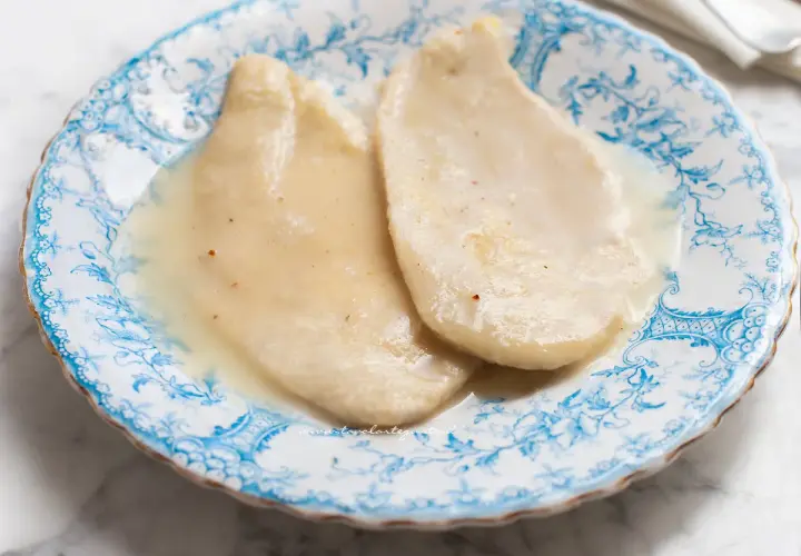 Due scaloppine al vino bianco, tenere e succulente, servite su un piatto di ceramica decorato con motivi blu.