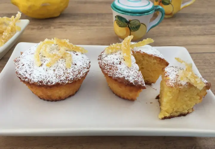 Deliziosi muffin caprese al limone, spolverati di zucchero a velo e decorati con scorzette candite.