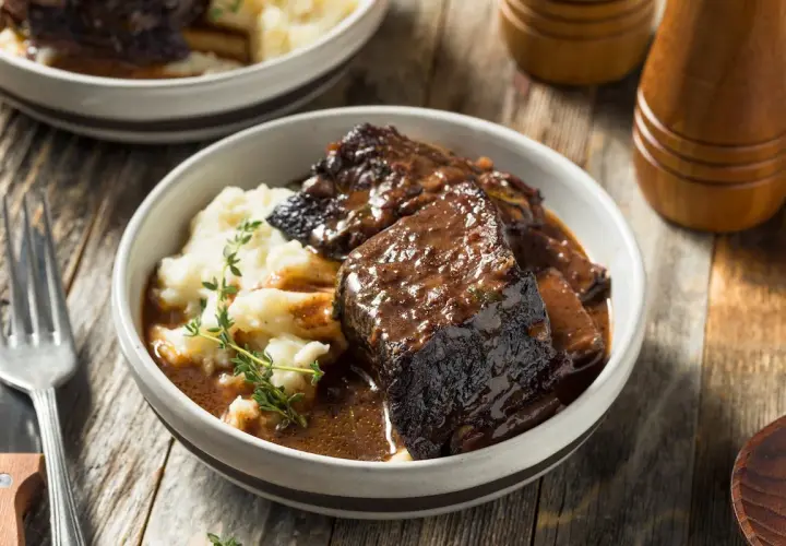 Un succulento brasato di manzo servito con purè di patate e guarnito con timo fresco.