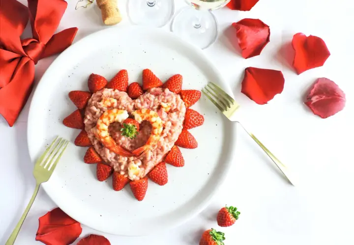 Un cuore di risotto alle fragole, decorato con gamberi e fragole fresche, pronto per un'occasione speciale.